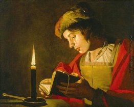 Junger Mann liest bei Kerzenlicht